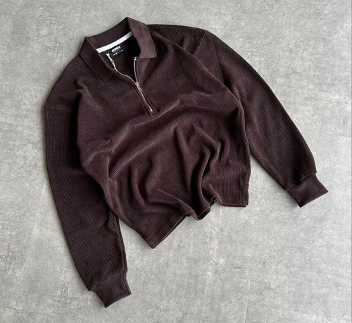 Brown sweater with a zipper on a gray concrete surface