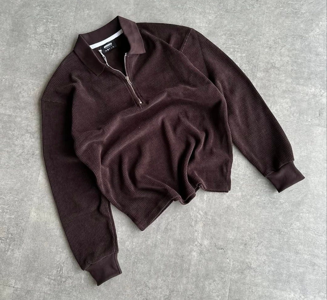 Brown sweater with a zipper on a gray concrete surface