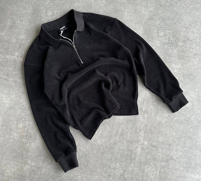 Black sweater with a zipper on a gray surface